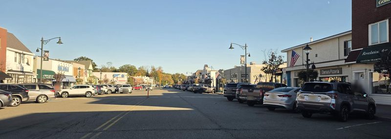 Storefronts, flags, and lamp posts along downtown Denville on a sunny fall afternoon
